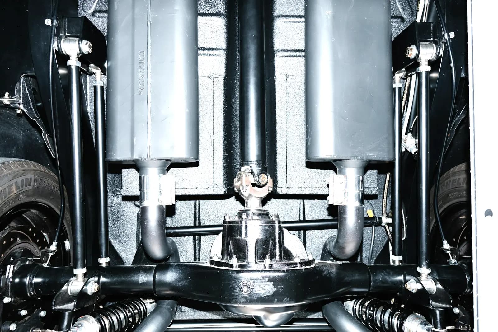 Underside of a rear-wheel-drive car, the driveshaft running into the differential housing at the center of the rear axle.