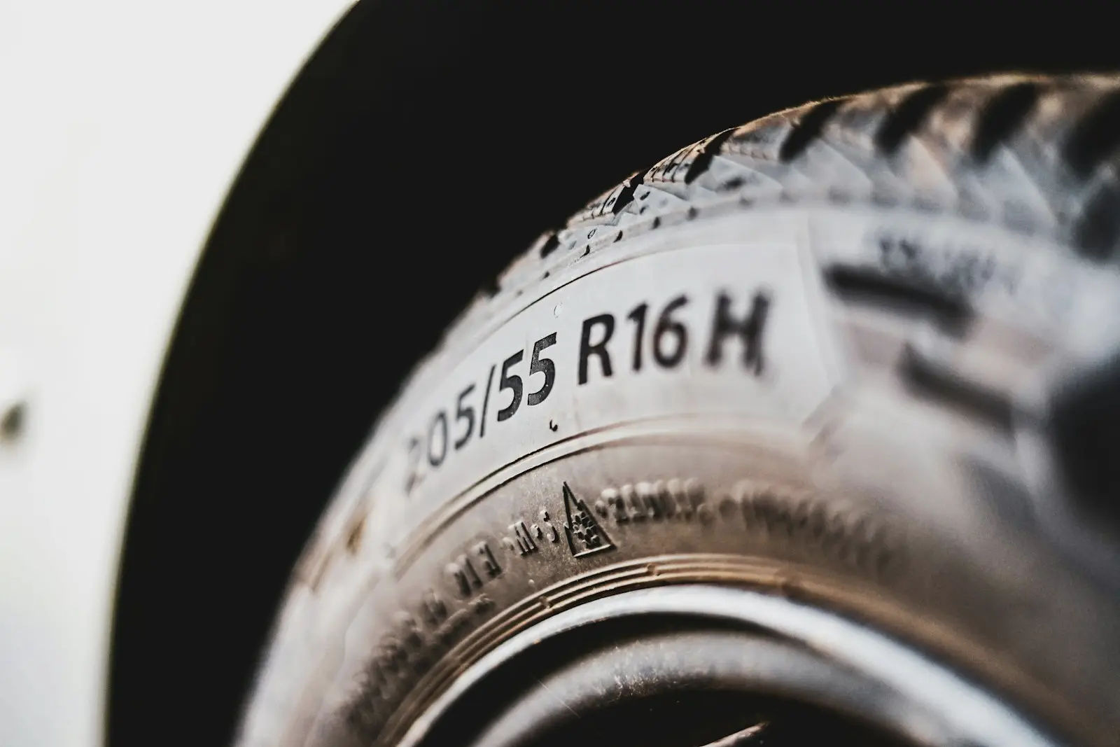 Close-up of a tire sidewall with the size 205/55 R16 H moulded in, and a mountain snowflake symbol below it.
