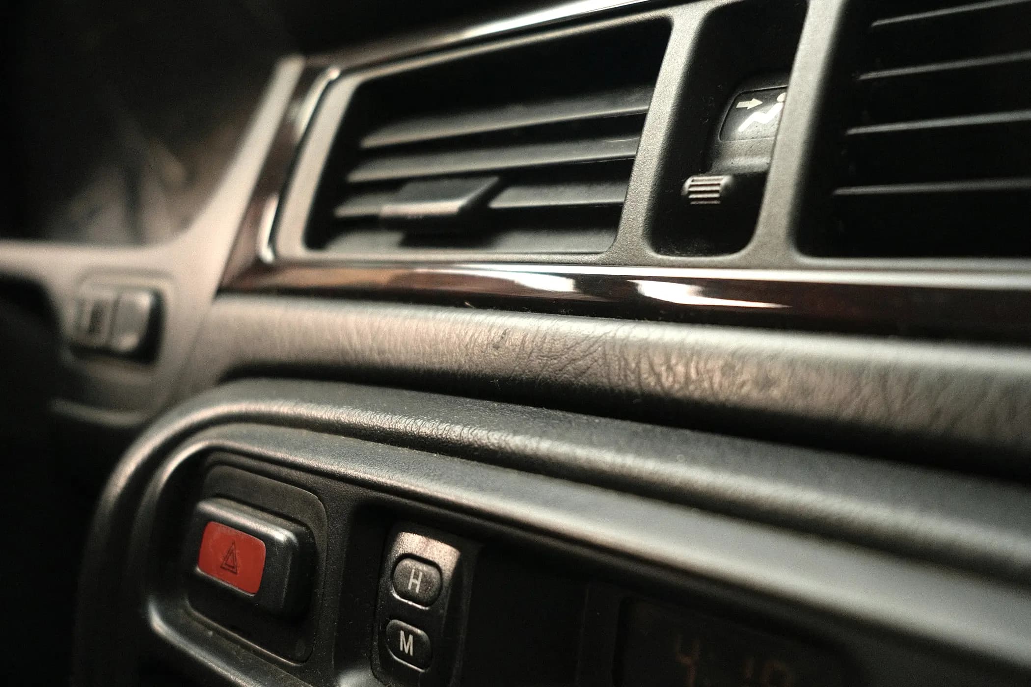 Centre dashboard air vents of a car, louvres open, with climate and hazard controls below.